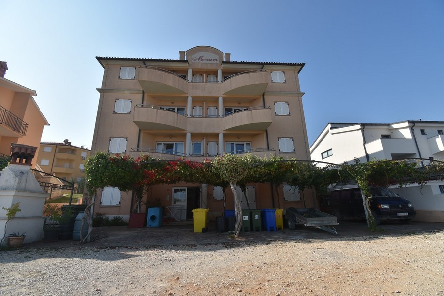 Edificio con balconi curvi dietro il pergolato di vite
