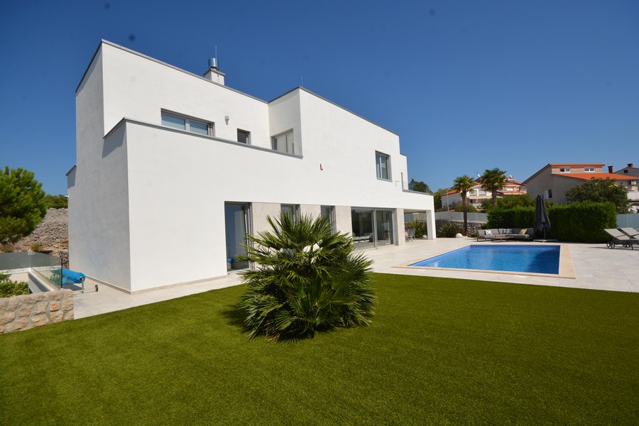 Villa bianca con palma nell'erba sintetica e piscina accanto