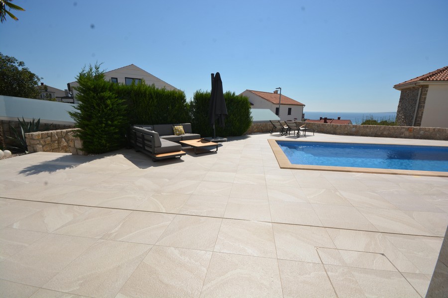 Ampia terrazza della piscina con lounge e siepe sul bordo