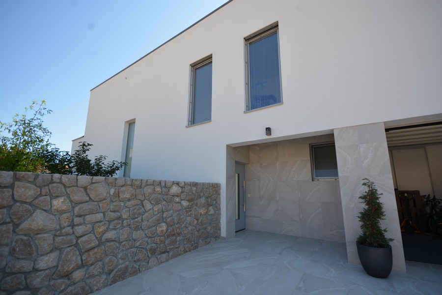 Lato d'ingresso con muro in pietra naturale e accesso coperto