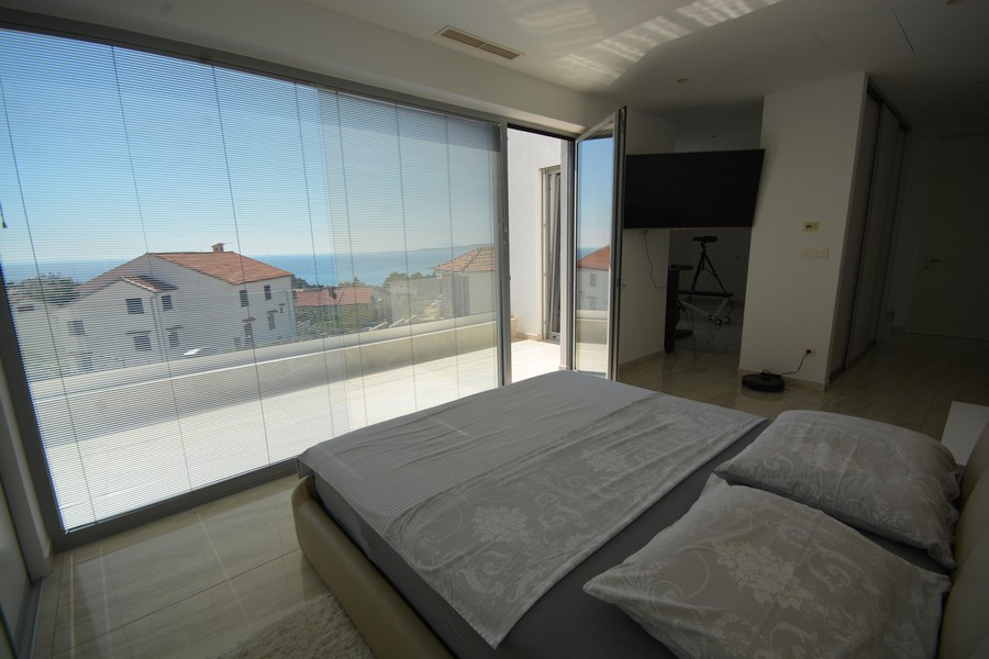 Camera da letto con finestra panoramica e veneziane verso il mare