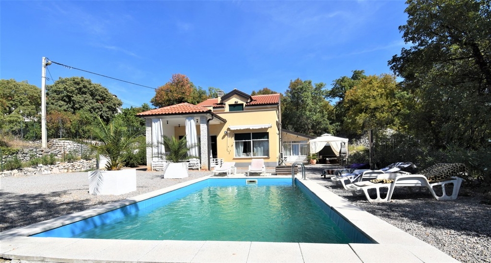 Lunga piscina con lettini davanti alla casa gialla