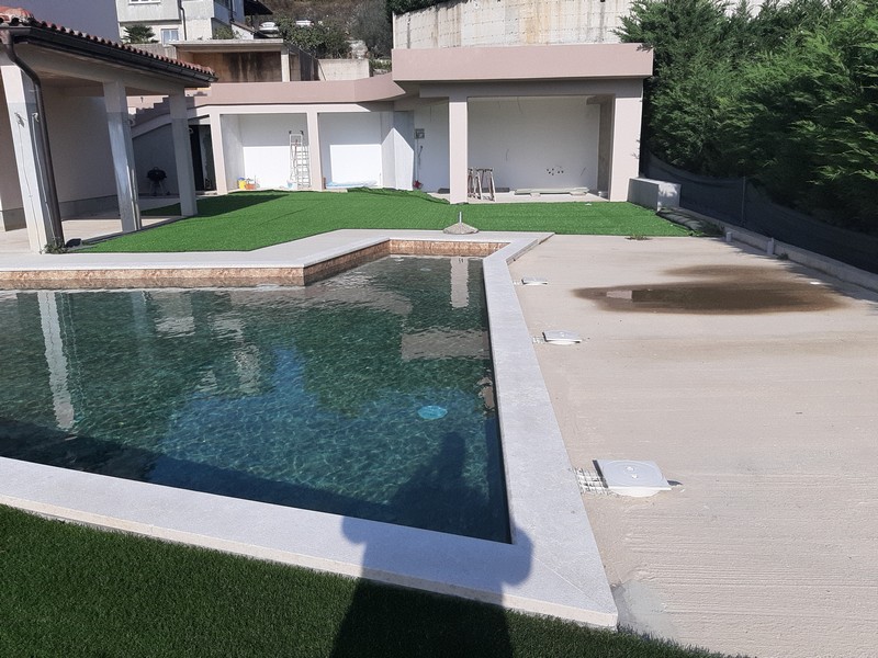 Piscina con rivestimento scuro davanti ai garage