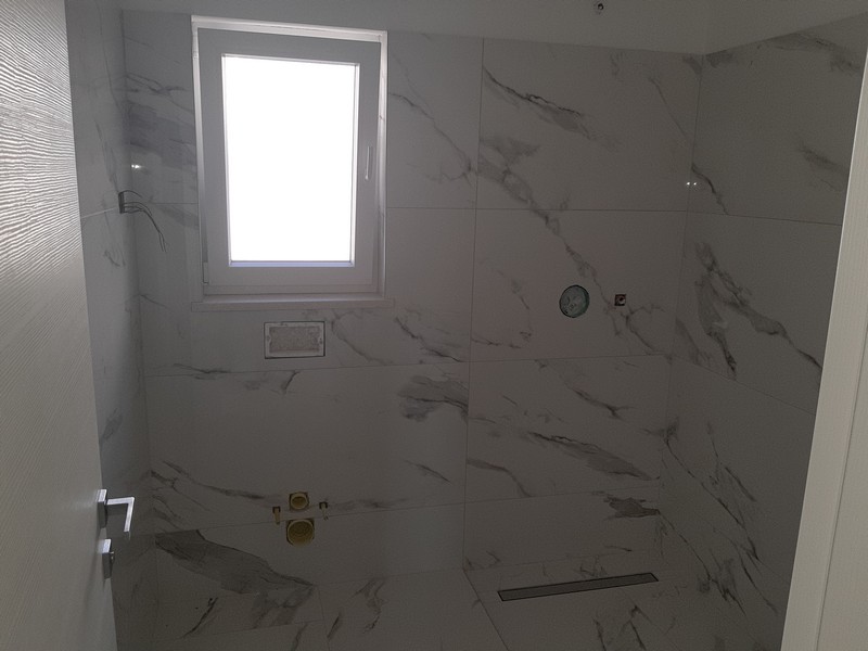 Bagno con piastrelle effetto marmo e finestra