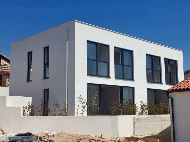 Edificio nuovo bianco con finestre scure dietro il muro