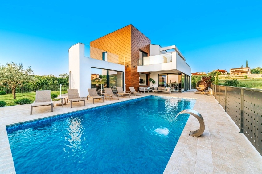 Piscina con lettini e getto d'acqua davanti alla villa