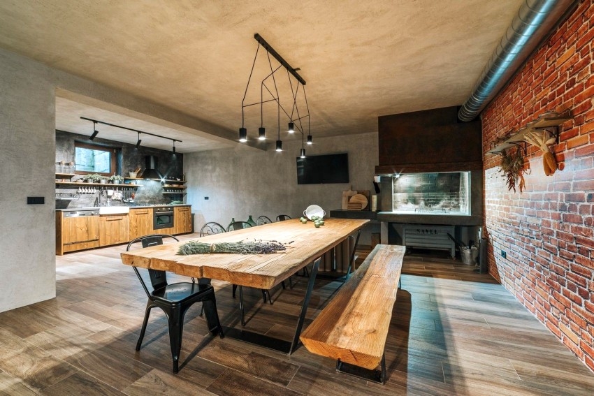 Tavolo da pranzo in legno massello davanti al muro di mattoni e alla cucina aperta