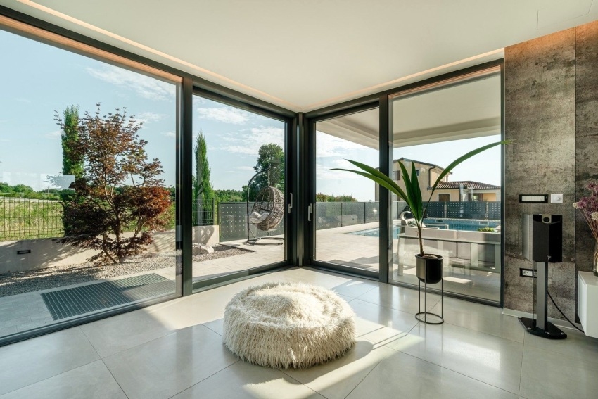 Stanza con vetrata d'angolo e pouf con vista sulla piscina