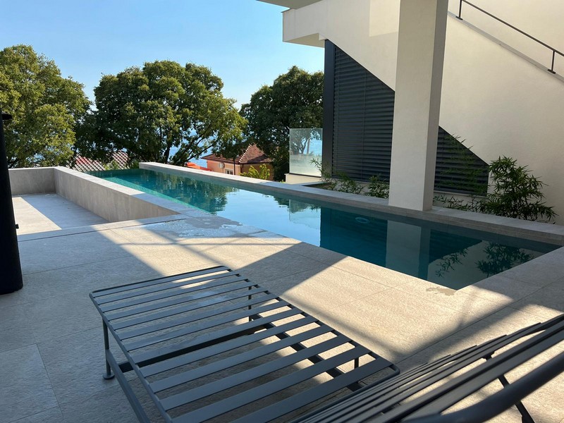 Piscina a sfioro con lettini accanto alla facciata chiara