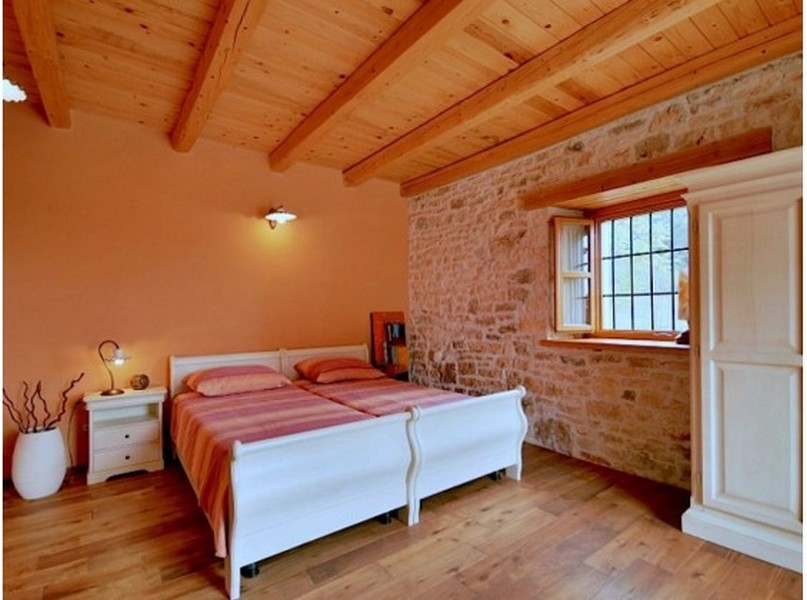 Camera da letto con due letti bianchi e parete in pietra naturale