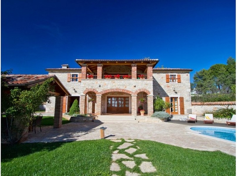 Casa in pietra con archi in mattoni e balcone sopra il giardino