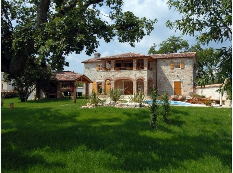 Casa in pietra con portici e piscina dietro il prato