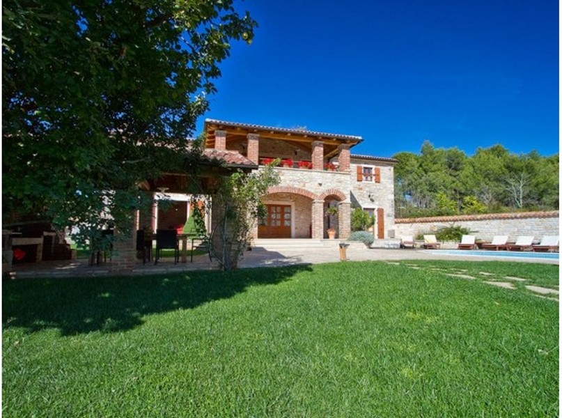 Villa in pietra con loggia e fioriere sopra il prato