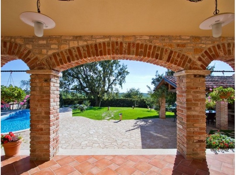 Vista attraverso gli archi in mattoni sul giardino e sulla piscina