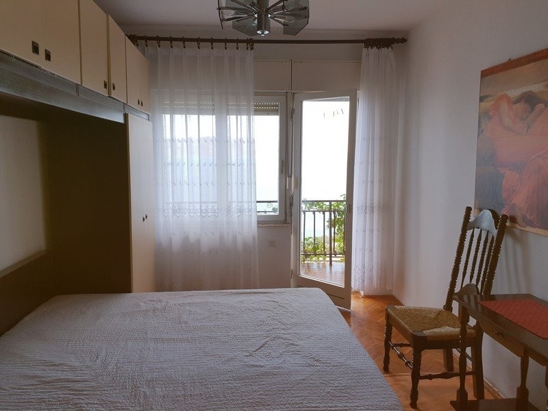 Camera da letto con armadio a ponte e porta sul balcone con tende