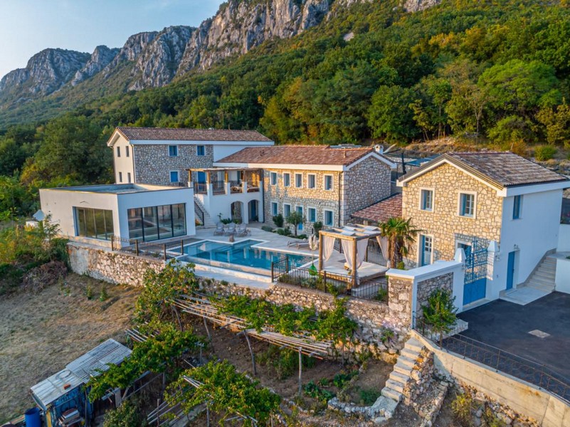 Tenuta di case in pietra con piscina davanti alla parete montuosa