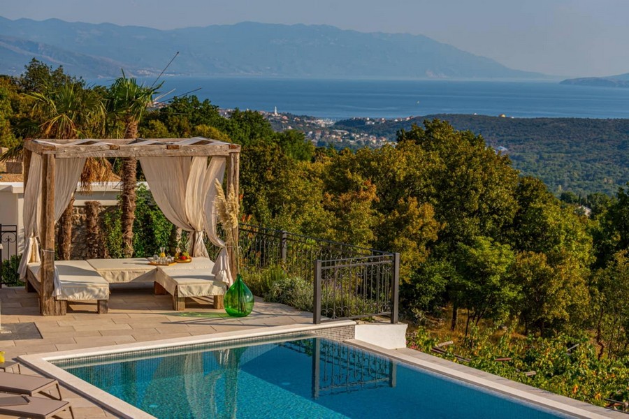 Lounge con tende a bordo piscina sopra la costa