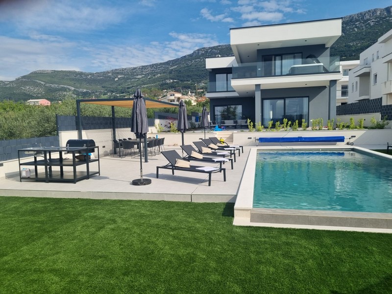 Piscina con lettini e ombrelloni davanti alle montagne