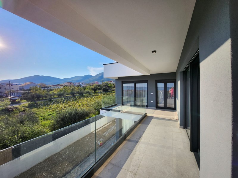 Loggia con parapetto in vetro e vista sui prati fino alle montagne