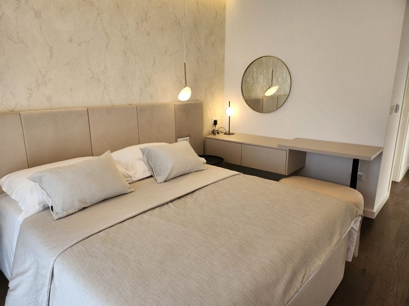 Camera da letto con letto matrimoniale e specchio rotondo sopra il mobile