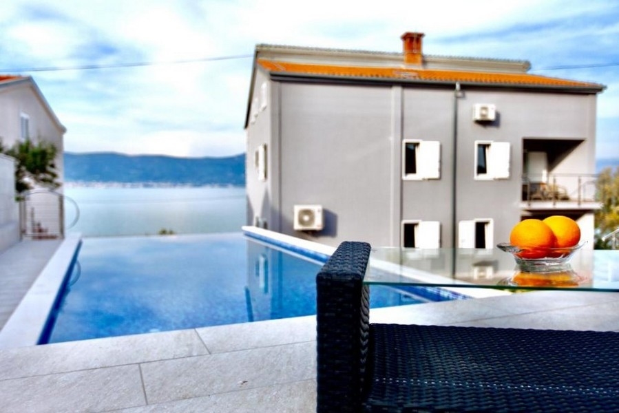 Piscina davanti alla casa con cesto di frutta sul tavolo