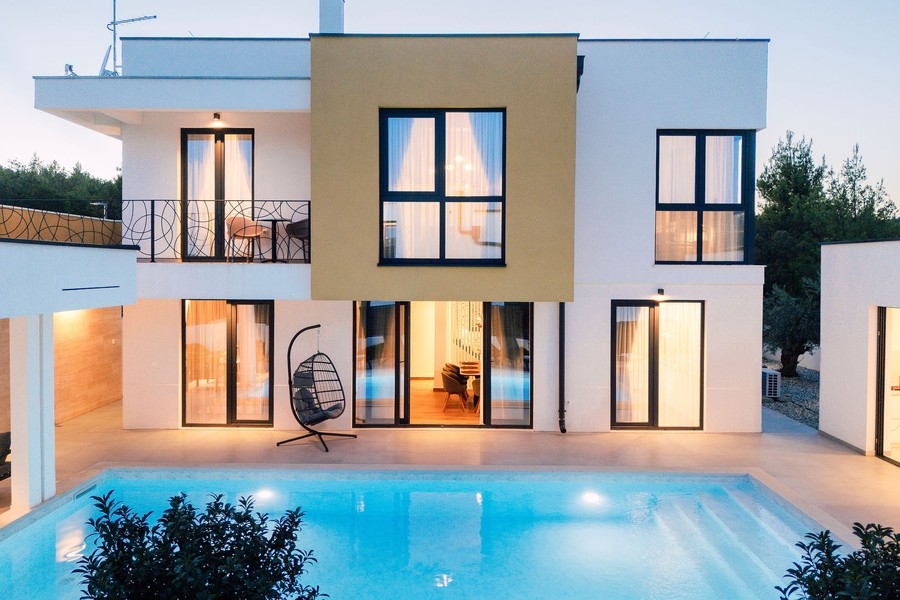 Facciata della casa con piscina illuminata e sedia sospesa