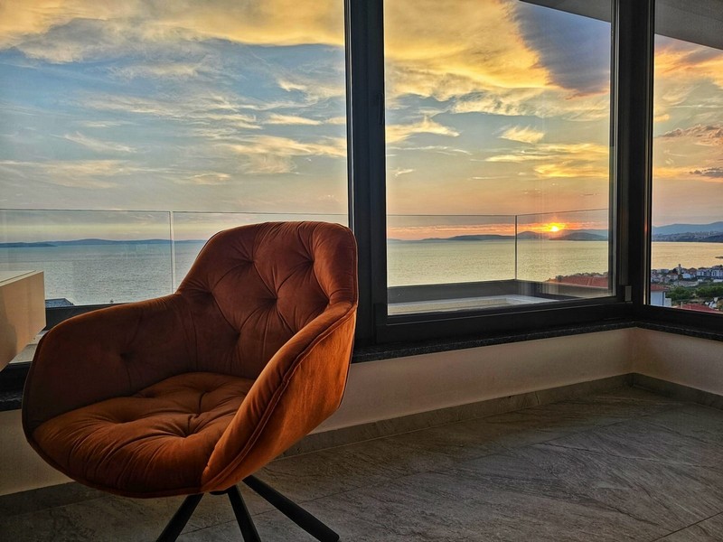 Poltrona alla finestra d'angolo davanti al tramonto sul mare