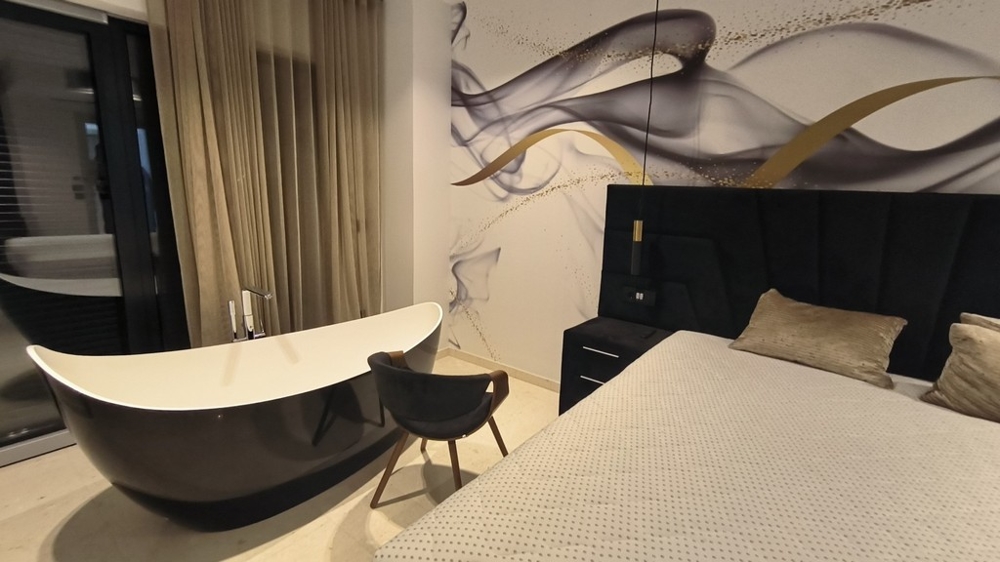 Camera da letto con vasca da bagno freestanding e pareti decorate con stile