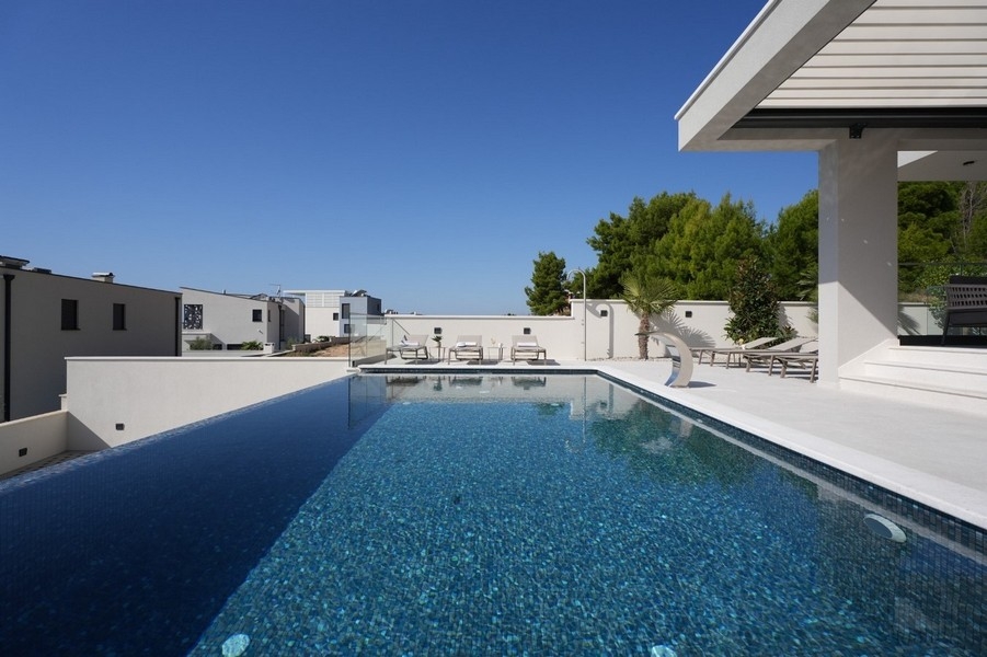 Lunga piscina accanto alla villa sotto un cielo azzurro