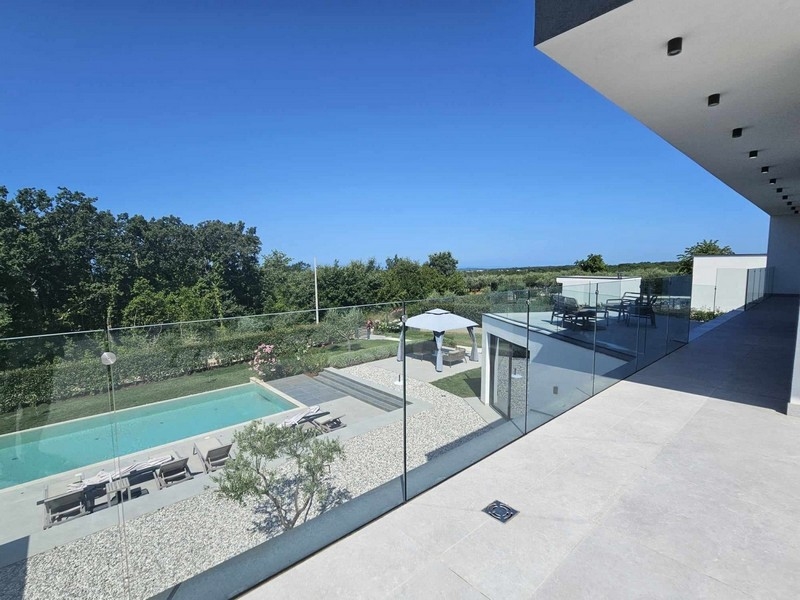 Vista dalla loggia sulla piscina e sul giardino fino al verde