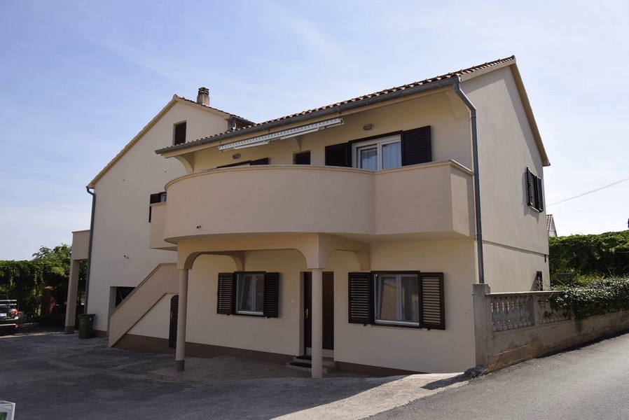Casa gialla con balcone rotondo e scala esterna verso l'appartamento