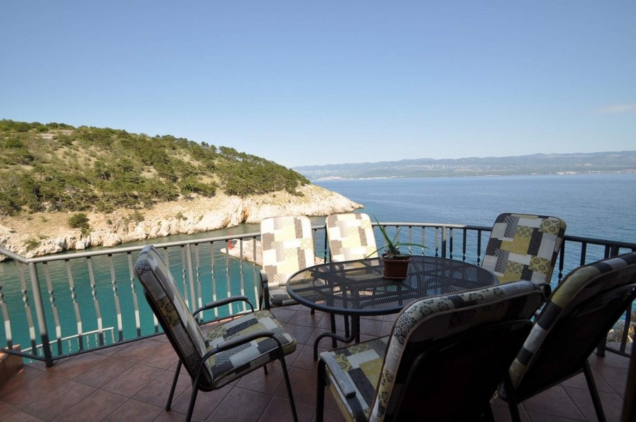 Balcone con mobili da giardino direttamente sopra la baia rocciosa