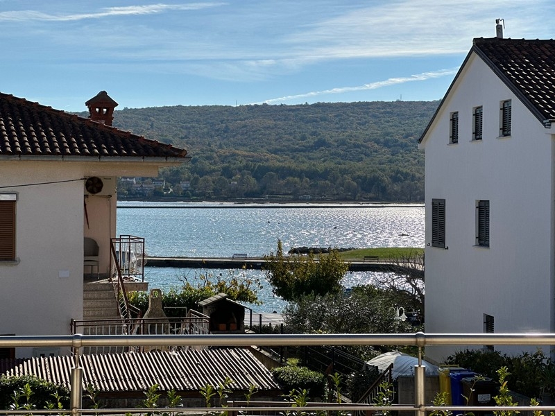 Vista tra due case sulla baia fino al pendio boscoso