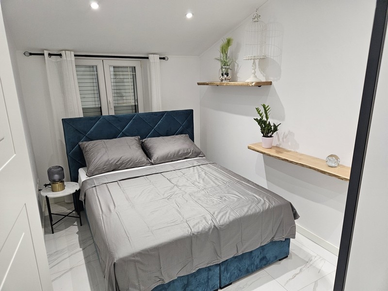 Accogliente camera da letto con testiera blu e piante decorative in un immobile in Croazia