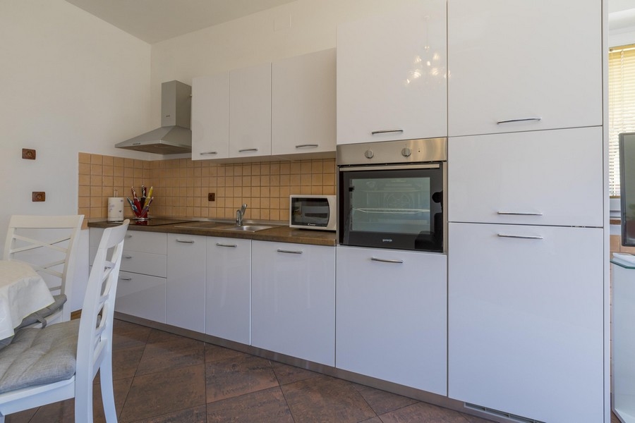 Cucina moderna bianca con zona pranzo in un immobile sul mare in Croazia
