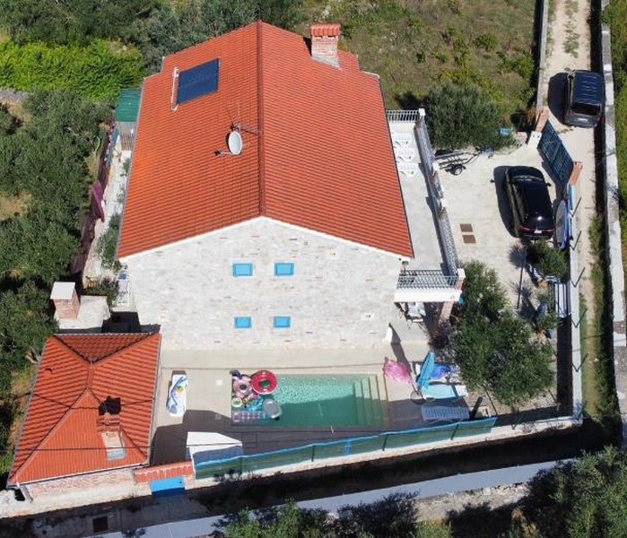 Ripresa aerea di una casa in pietra in vendita in Croazia, con giardino e piscina.