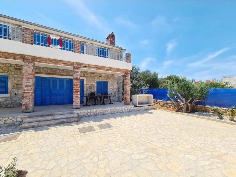 Vista frontale di un grazioso casa in pietra in vendita in Croazia con zona pranzo all'aperto.