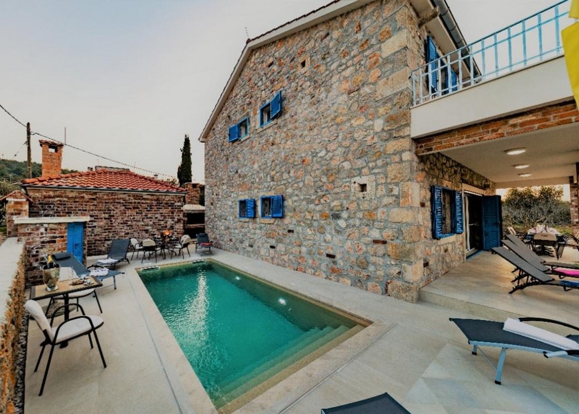 Lussuosa casa in pietra in Croazia in vendita con area lounge in piscina e ambiente tranquillo.