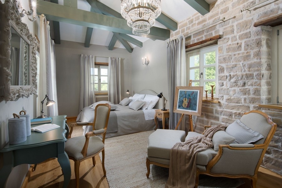 Camera da letto con parete in pietra e lampadario nella villa in Istria