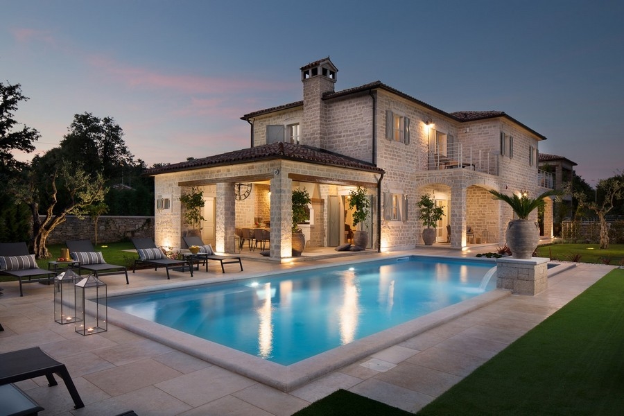 Villa di lusso in Croazia al crepuscolo con piscina illuminata e sdraio.
