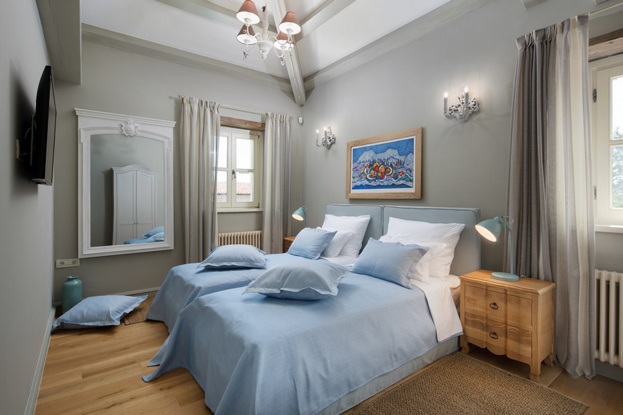 Confortevole camera da letto in una villa croata con biancheria blu e pavimento in legno.