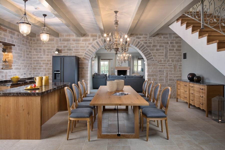 Zona giorno e pranzo aperta con tavolo in legno ed eleganti lampade in una villa croata.