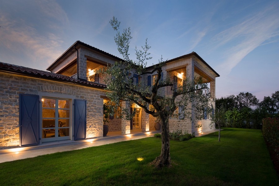 Villa con facciata in pietra illuminata e persiane blu a Kanfanar
