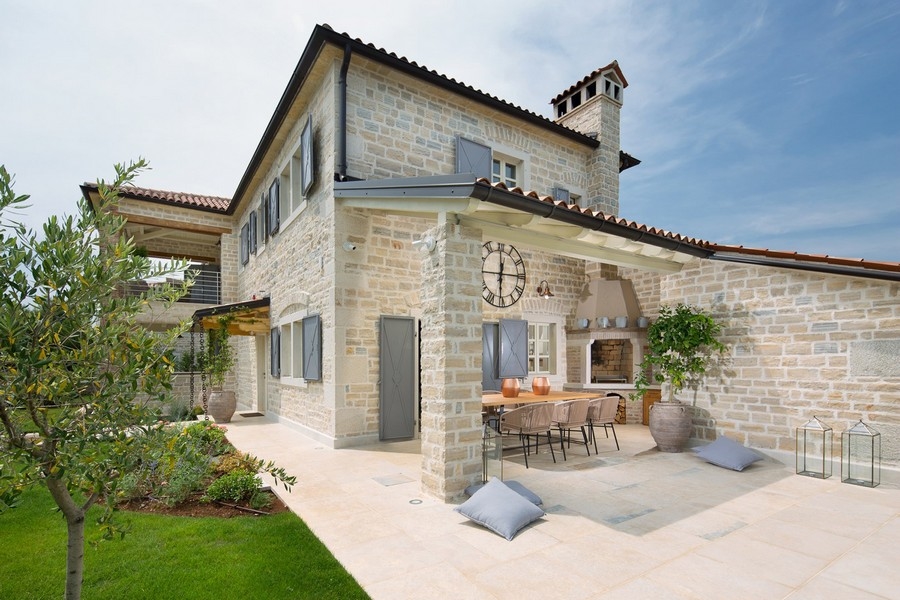 Patio esterno con zona pranzo e camino in muratura in una villa