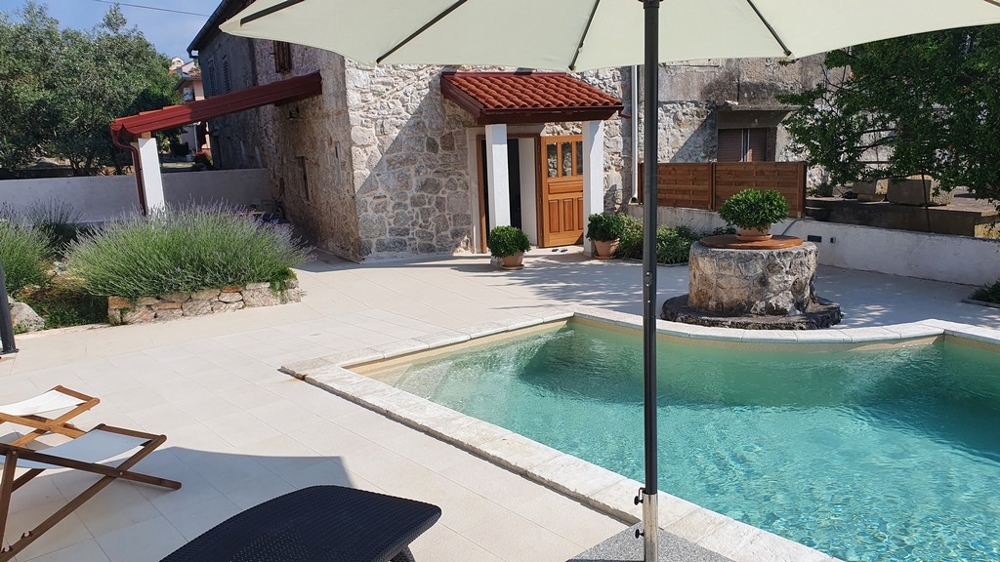 Area piscina dal design moderno di un immobile in Croazia con sdraio e ombrellone