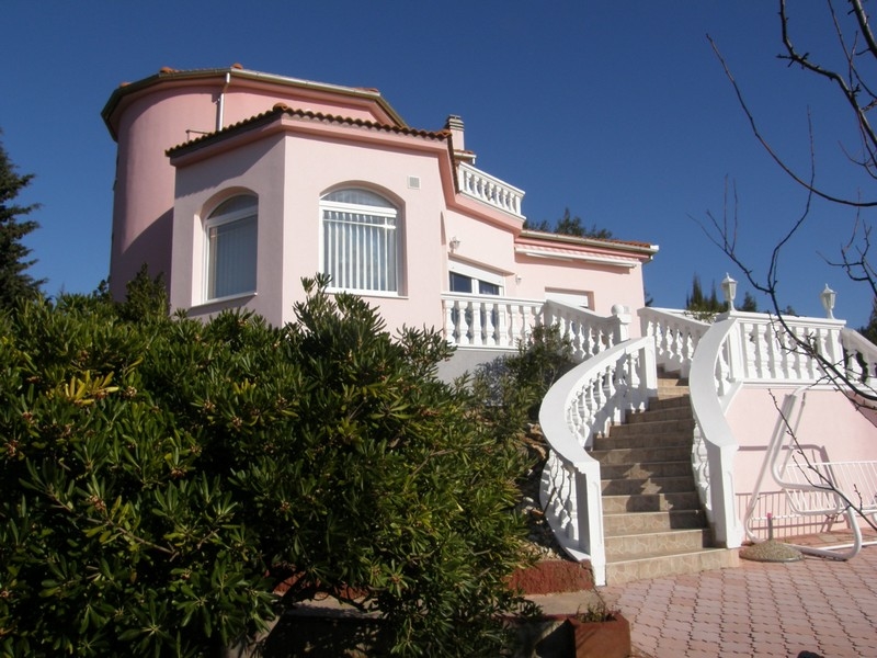 Villa rosa in vendita in Croazia con ringhiere bianche e scala d'accesso circondata da piante verdi