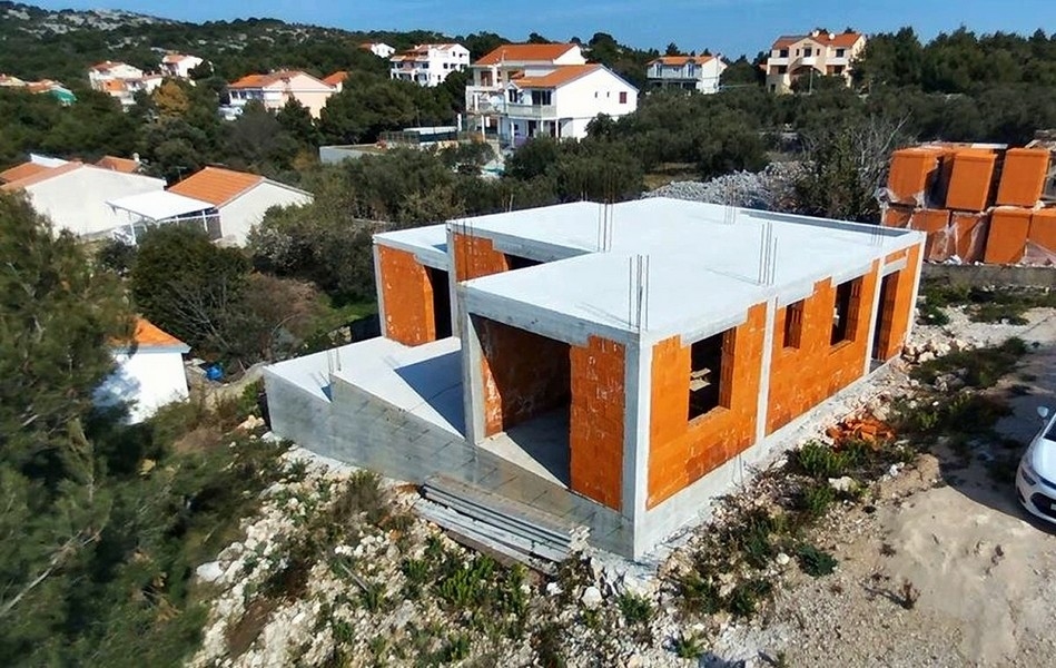 Vista di dettaglio della costruzione di una villa con pareti di mattoni non intonacate e pilastri in cemento, in vendita sull'isola di Krk in Croazia
