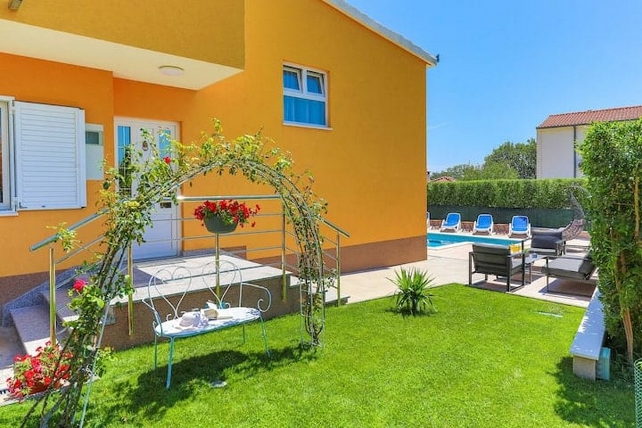 Giardino curato con prato e arco di rose della casa plurifamiliare a Kastel Luksic, Croazia