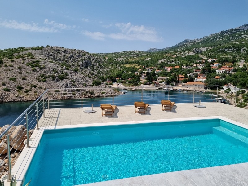 Piscina e terrazza con lettini e vista sulla baia