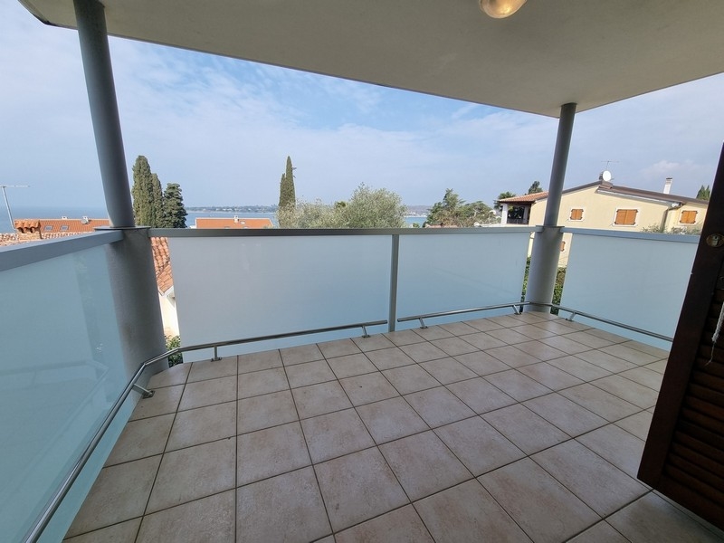 Loggia con pavimento piastrellato e vista su cipressi e baia